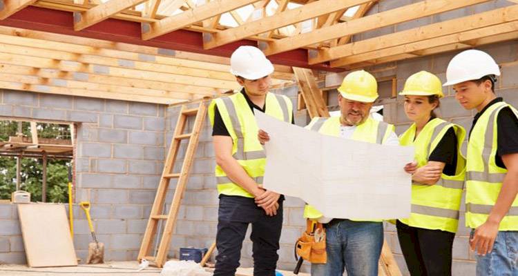tradespeople on a construction site looking at a building plan