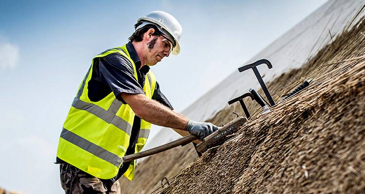 tradesperson installing a thatched roof