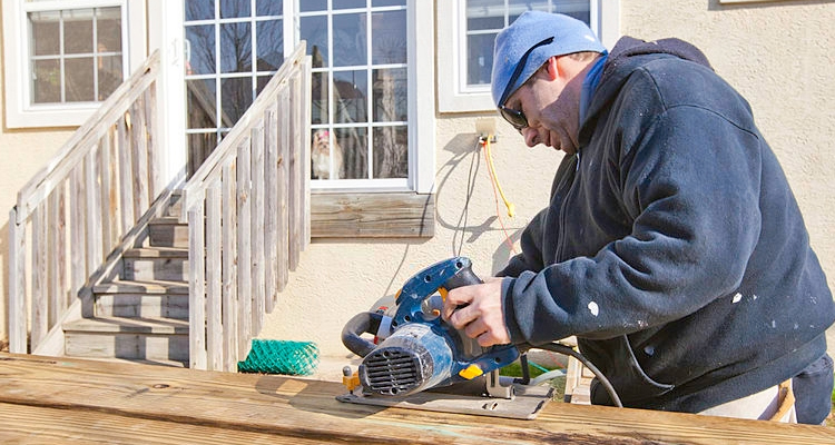 tradesperson cutting timber decking planks during an installation project