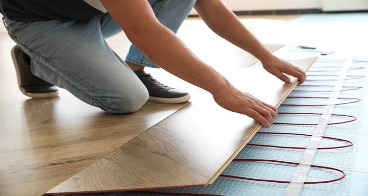 hands laying flooring on top of underfloor heating