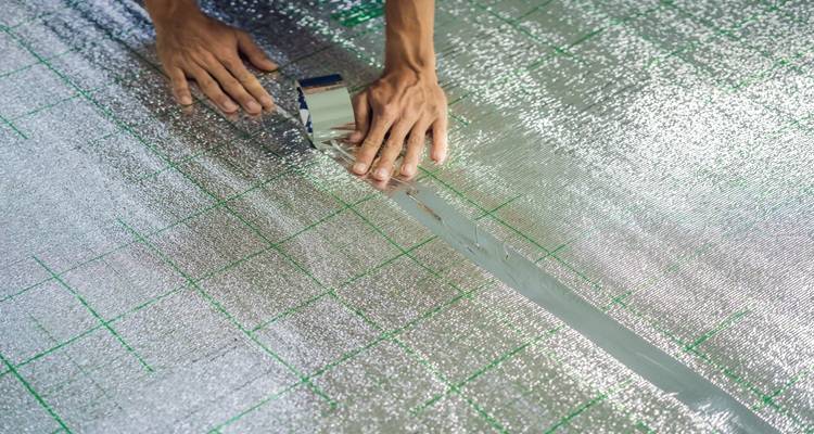 hand taping insulated underlay in place