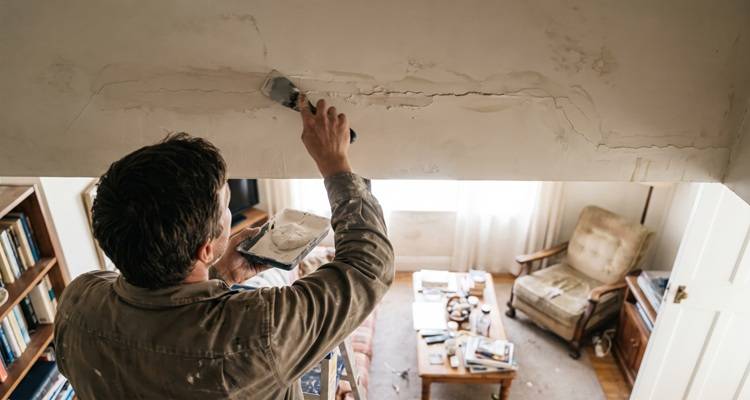 man up ladder repairing crack in wall