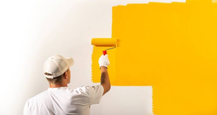 man painting white wall orange