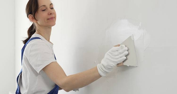 woman filling cracks in wall