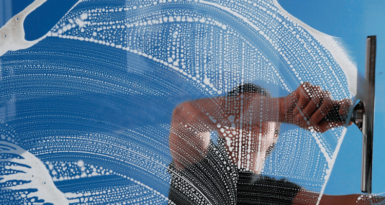 professional window cleaner using a squeegee